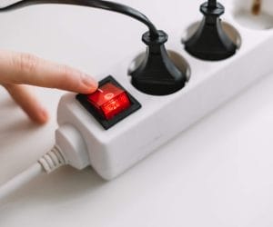 Hand turns on an electric surge protector. Protection of household appliances from electrical interference. Home safety