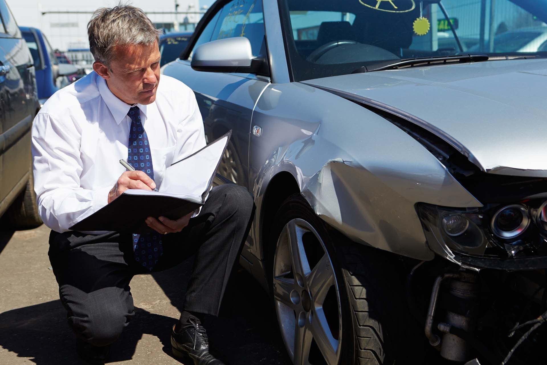 An insurance adjuster surveying a damaged car in Maryland.