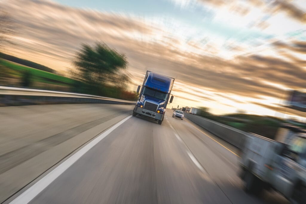 Fast-moving truck on highway at sunset